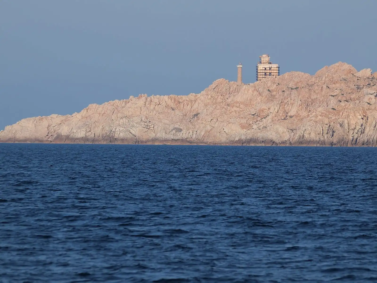 Faro di Razzoli sulla scogliera di granito visto dal mare