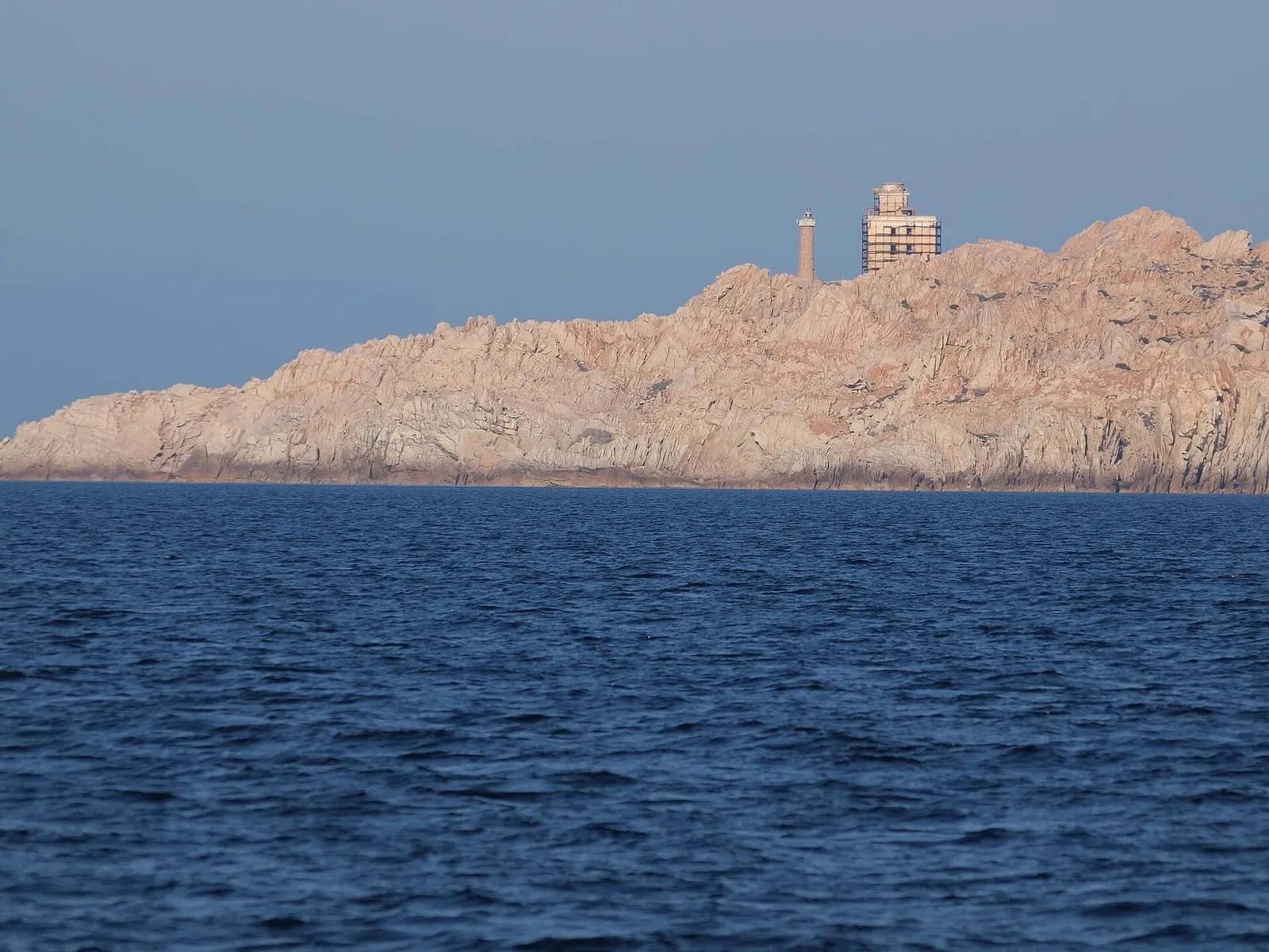 Faro di Razzoli sulla scogliera di granito visto dal mare