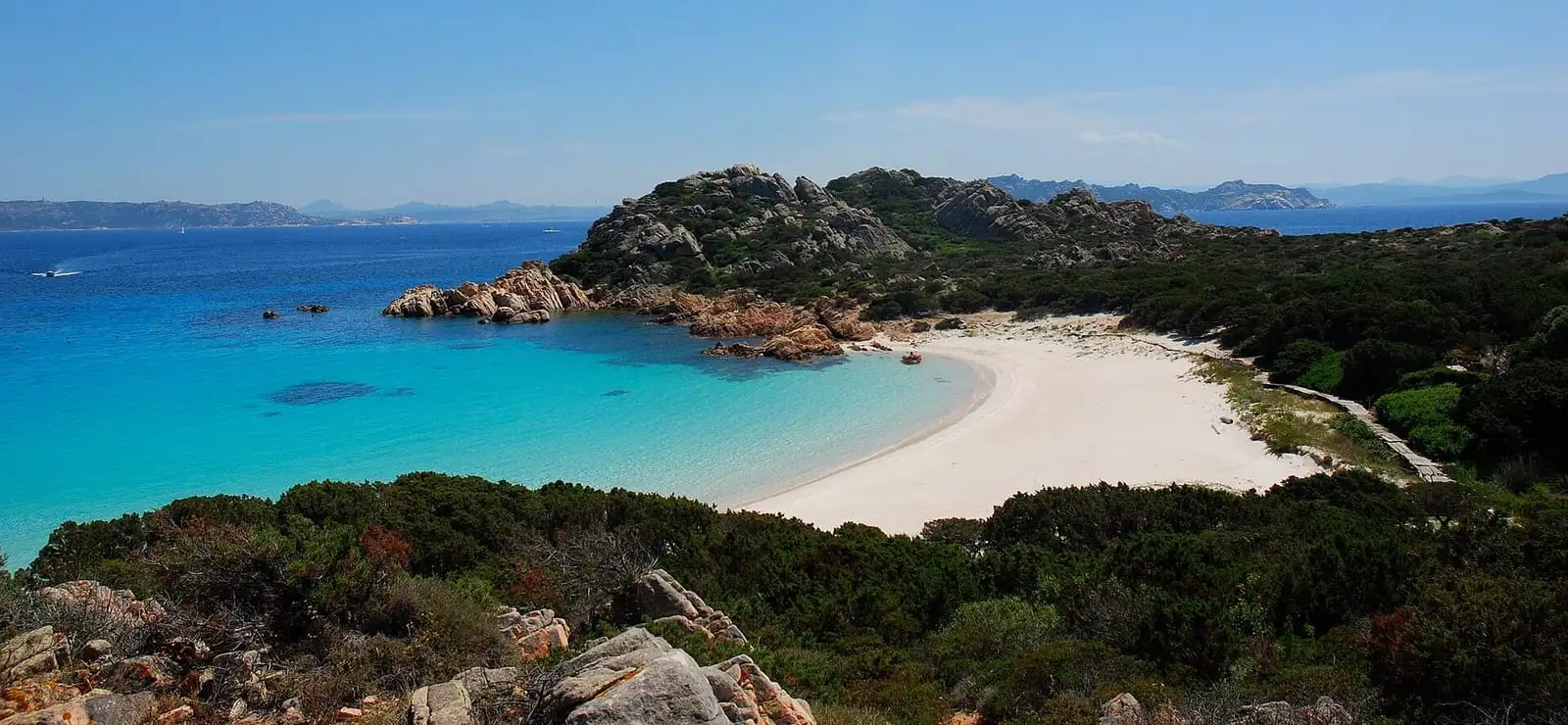 Panorama della Spiaggia Rosa di Budelli con la cala turchese e la macchia mediterranea